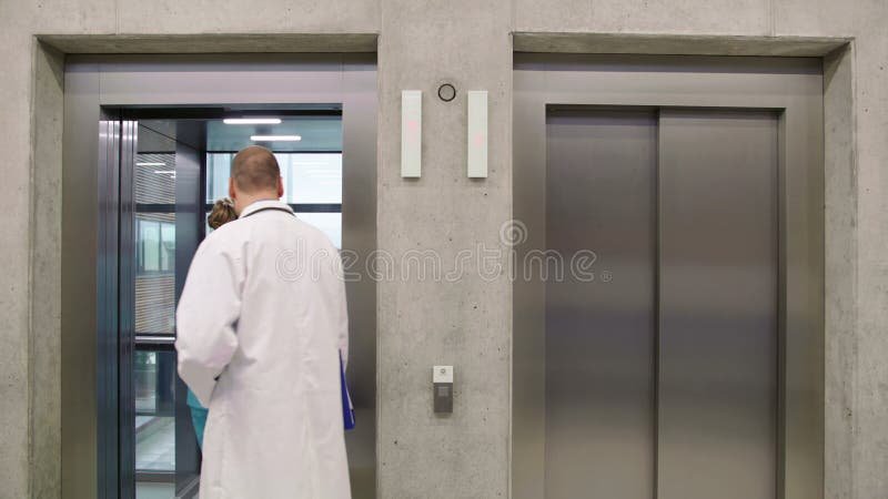 Doctor and nurse interacting with each other and entering in lift stock video footage