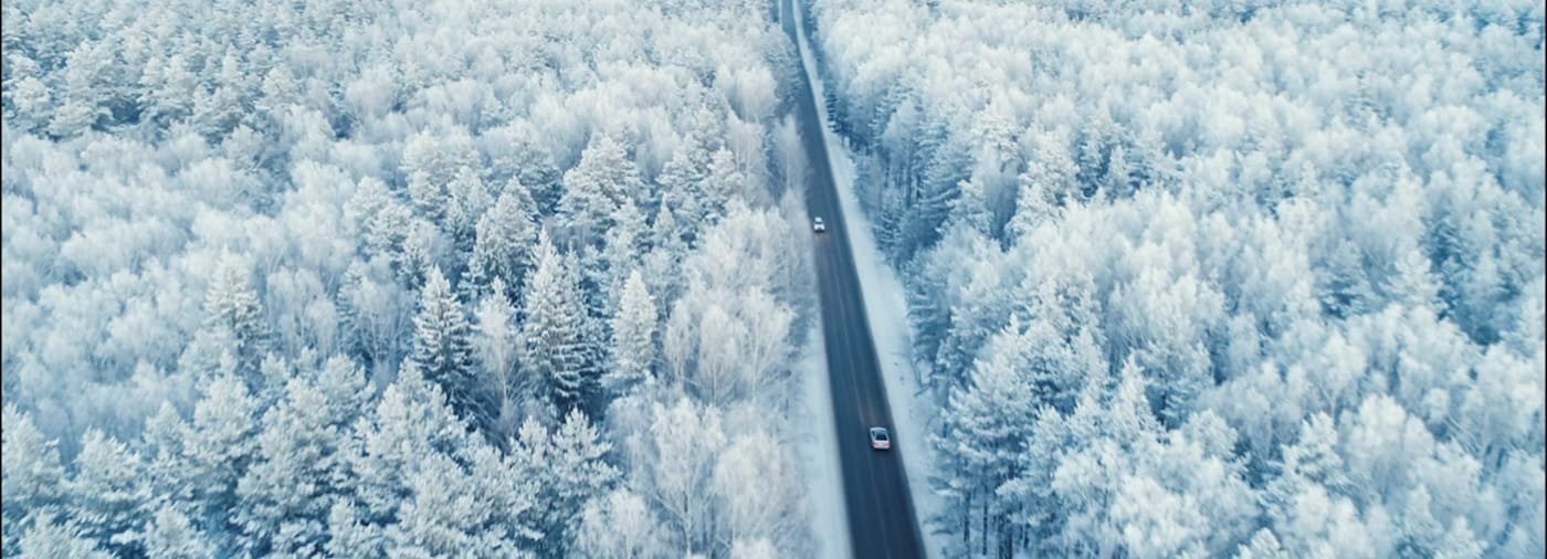 aerial view of a car driving on a snowy forest road k aerial view of a car driving on a snowy forest road